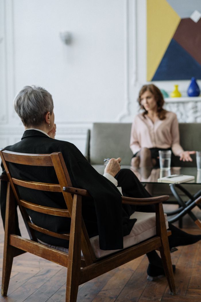 Home A therapist and patient engaged in a counseling session in a modern office setting.