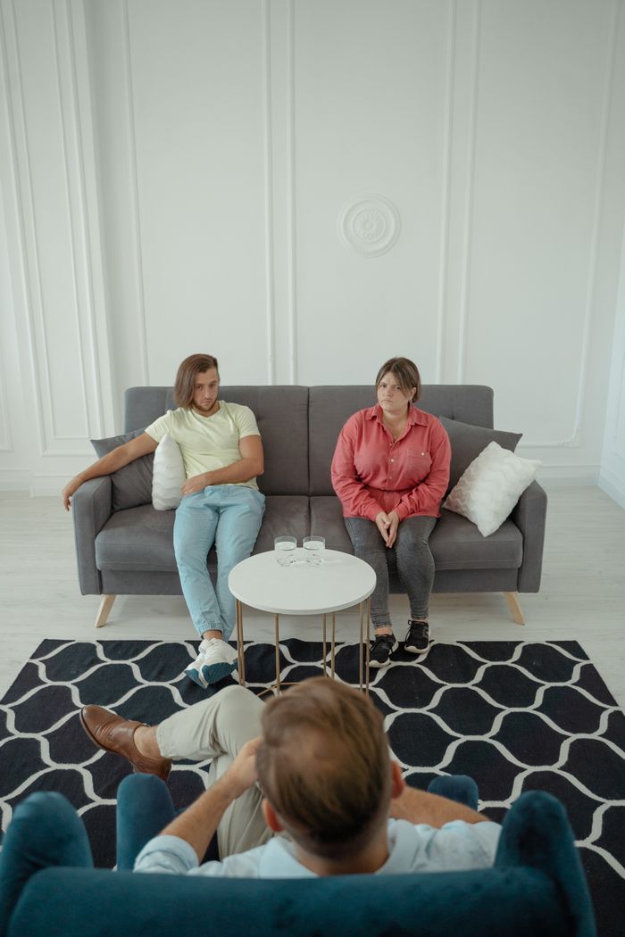Services A couple sitting on a sofa during a therapy session with a professional therapist.