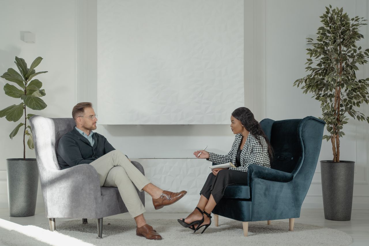 About A therapist and patient engaged in conversation in a modern, stylish therapy office.